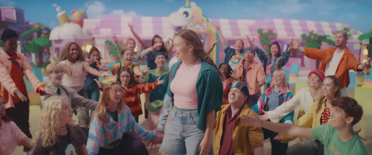 Young cast of the LEGO Friends musical dancing in a colourful Heartlake City street