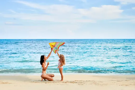 Mother and daughter flying a kite on a beach